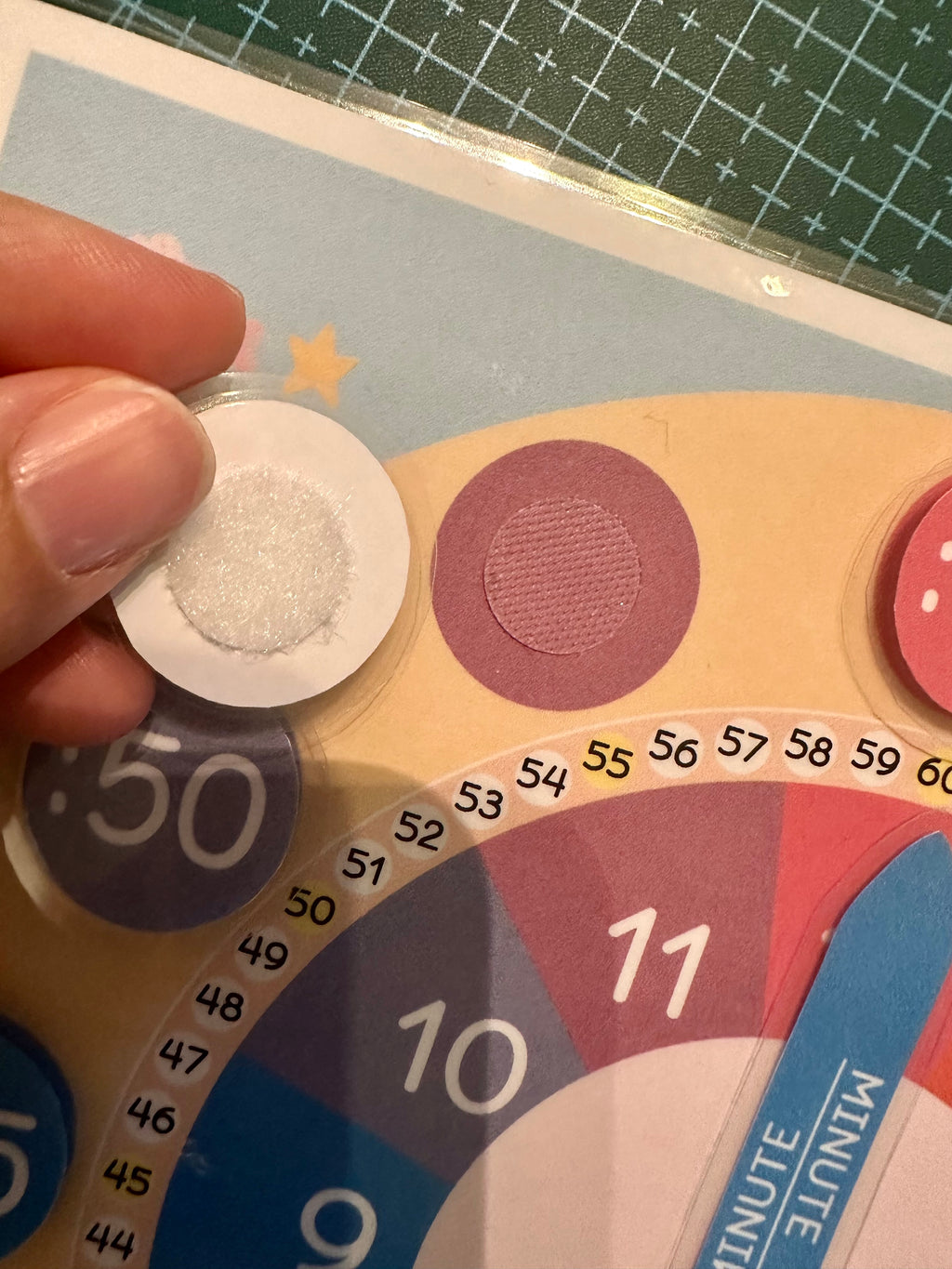 Hand holding the velcro minute over a the correct position of the clock.