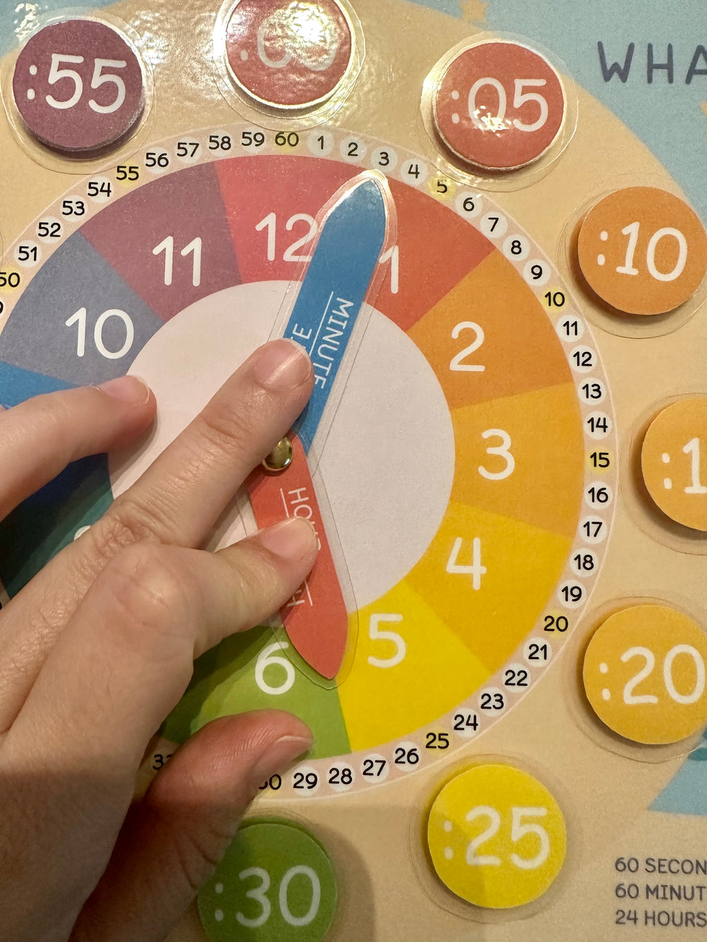 Wooden educational clock with colorful numbers and a hand pointing to a blue hour hand.