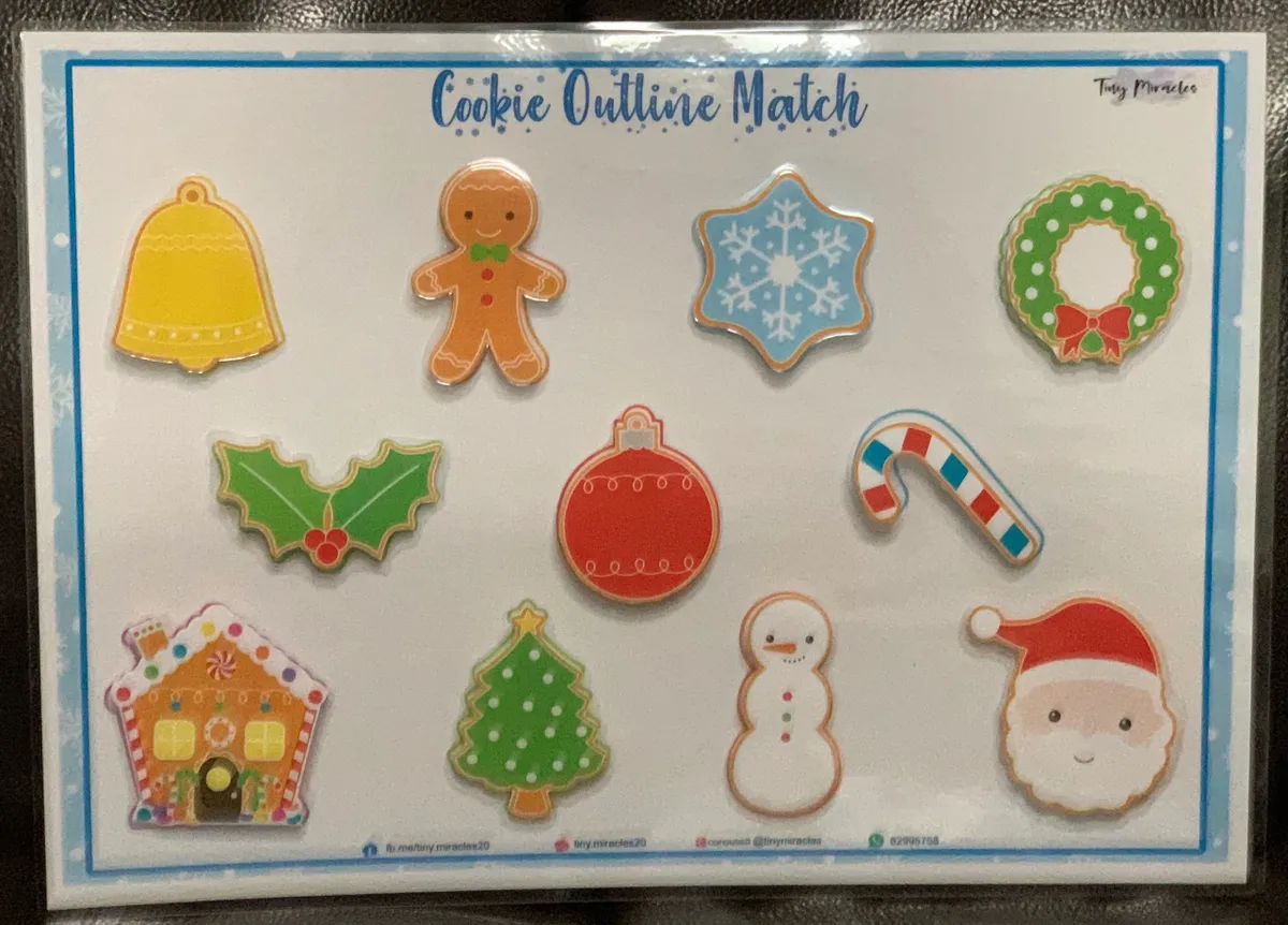 Set of Christmas-themed cookie cutters on a matching game board with text 'Cookie Outline Match'.